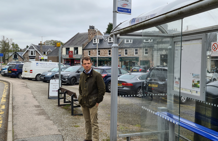 Andrew Bowie MP standing beside a bus stop in Aboyne.