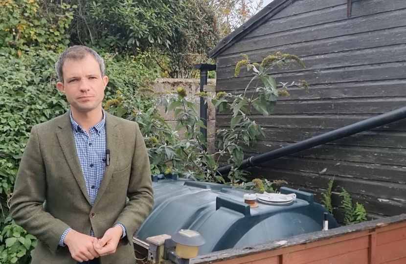 Andrew Bowie MP standing beside a heating oil tank.
