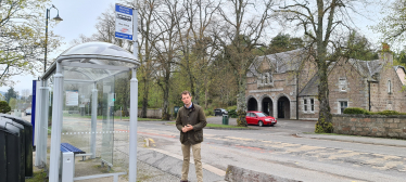 Andrew Bowie MP beside a bus stop in Aboyne.